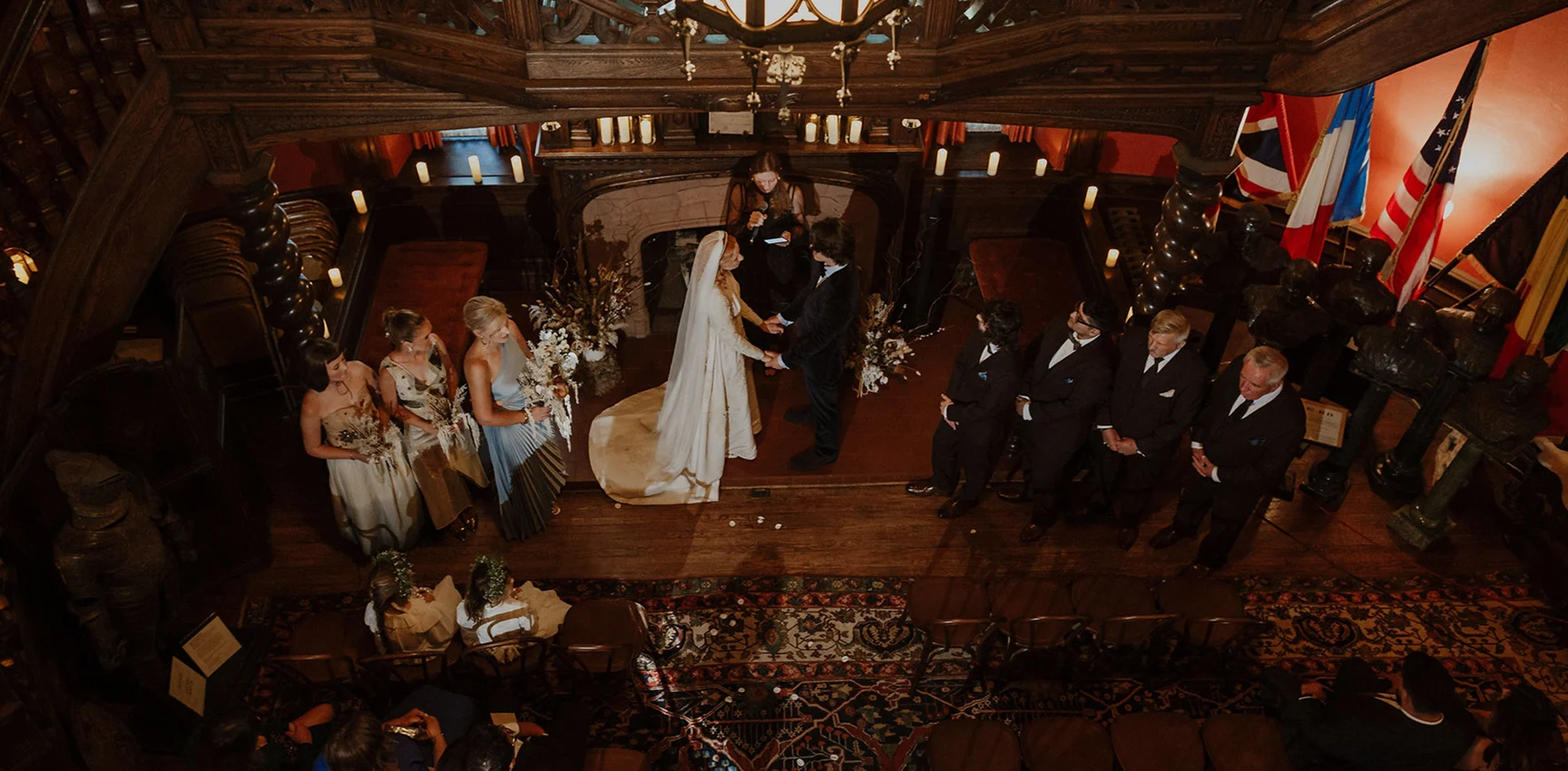 A photo of a wedding ceremony, bride and groom next to the officiant, guests around