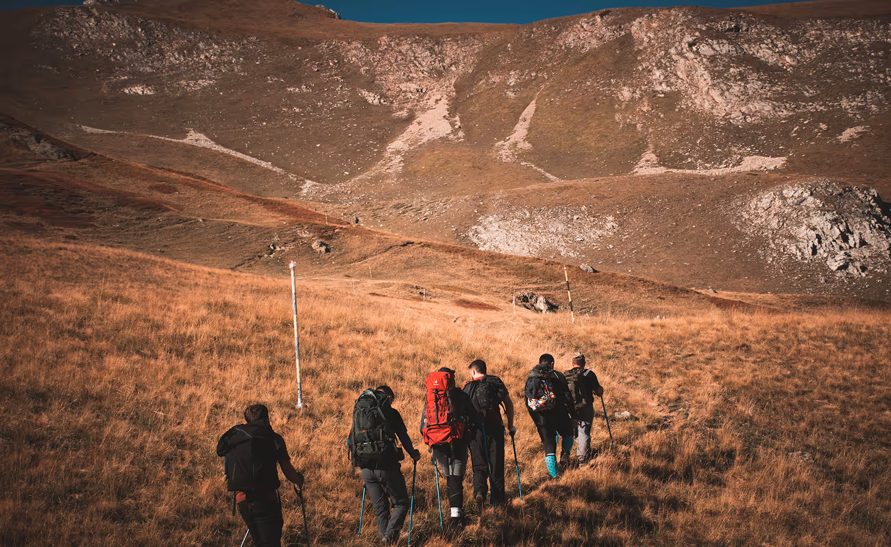 Group of hikers beginning a trail, walking toward a hill or mountain in the distance.