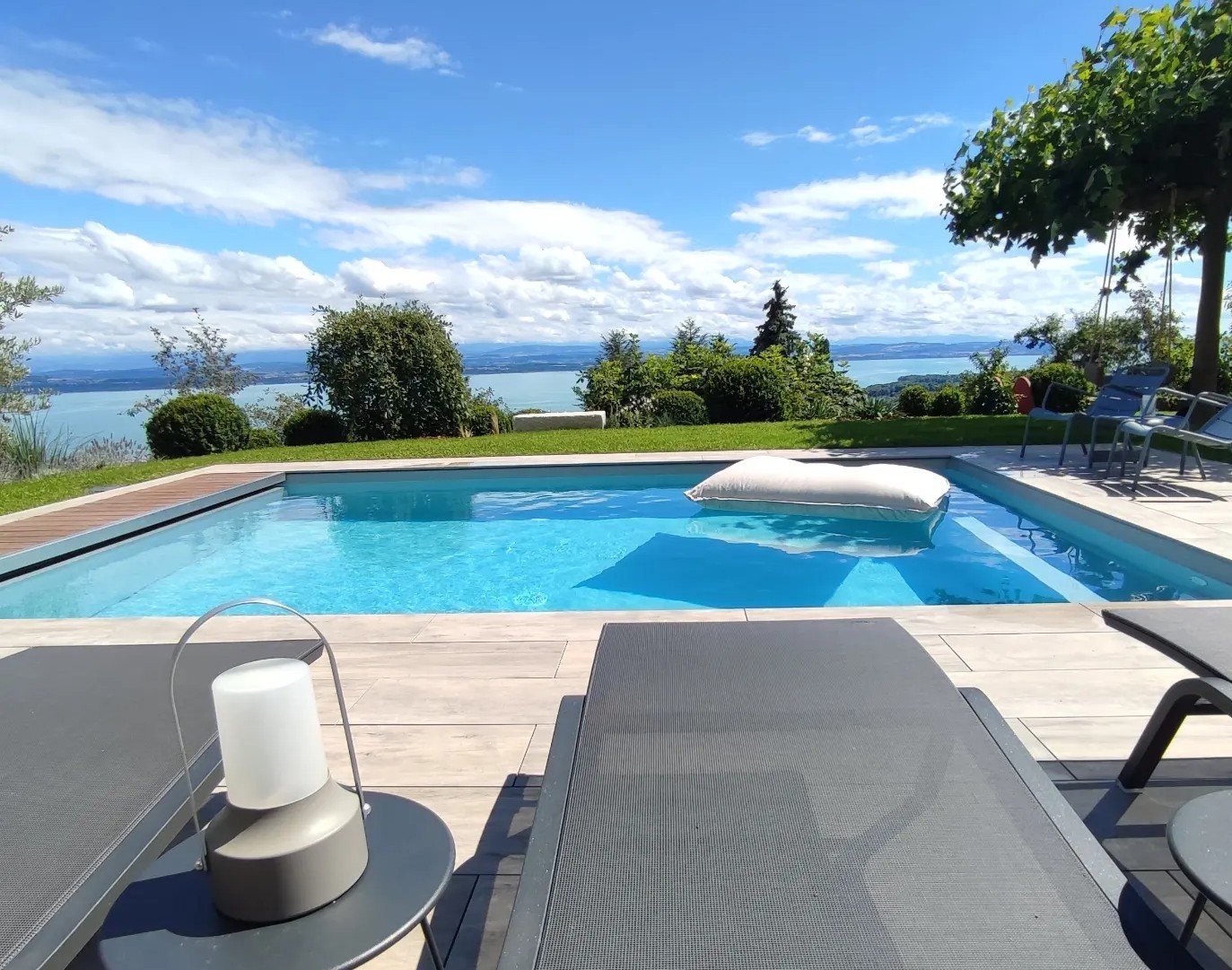 Piscine avec terrasse et vue sur le lac, réalisée par Espace Piscines et Spas.