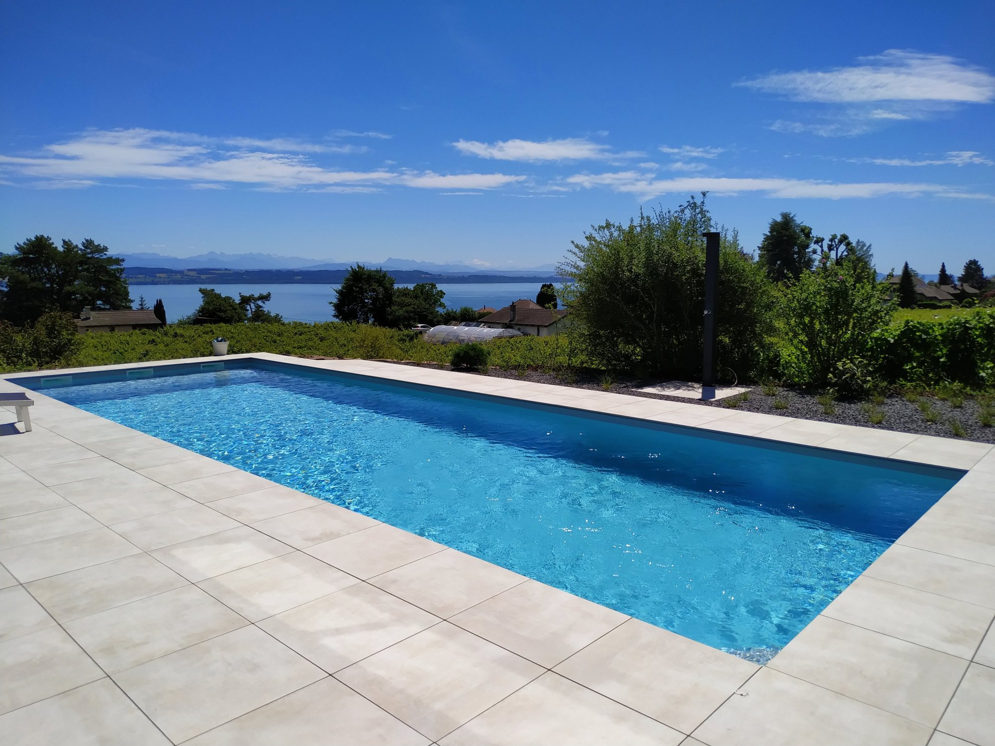 Piscine traditionnelle avec vue sur le lac, réalisée par Espace Piscines et Spas.