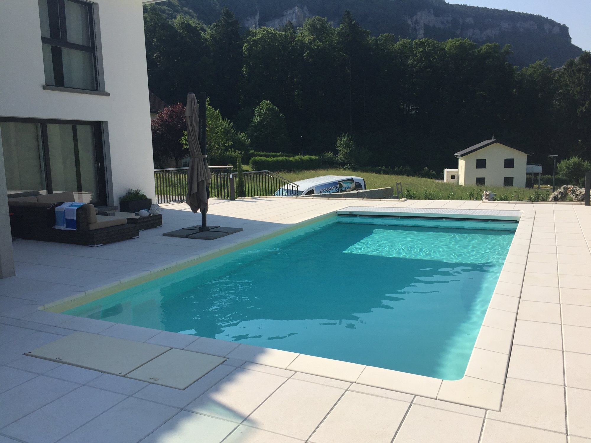 Piscine avec grande terrasse en dallage, réalisée par Espace Piscines et Spas.
