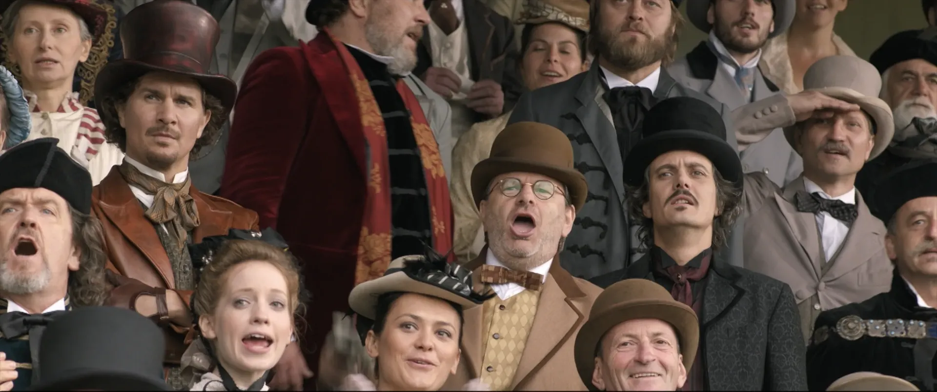 Sophisticated people watching horseracing from the stands all wearing historically accurate eccentric clothing.
