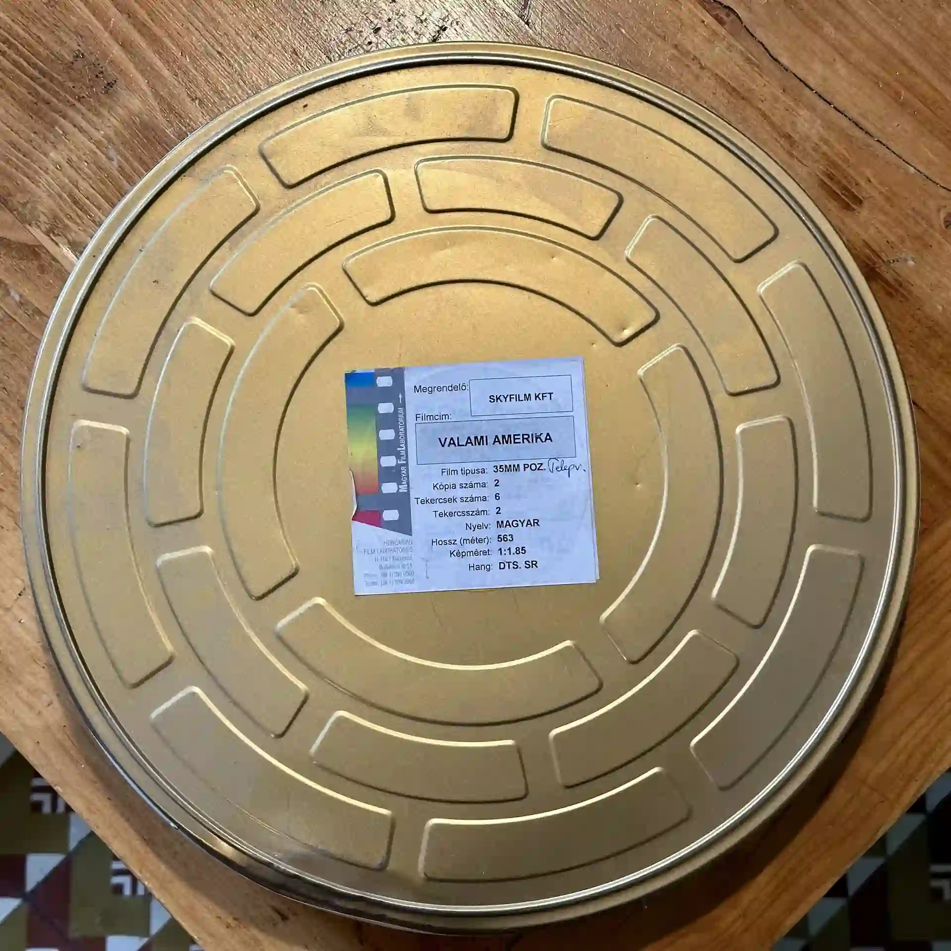 A round metal film canister with a label on top sits on a wooden surface.