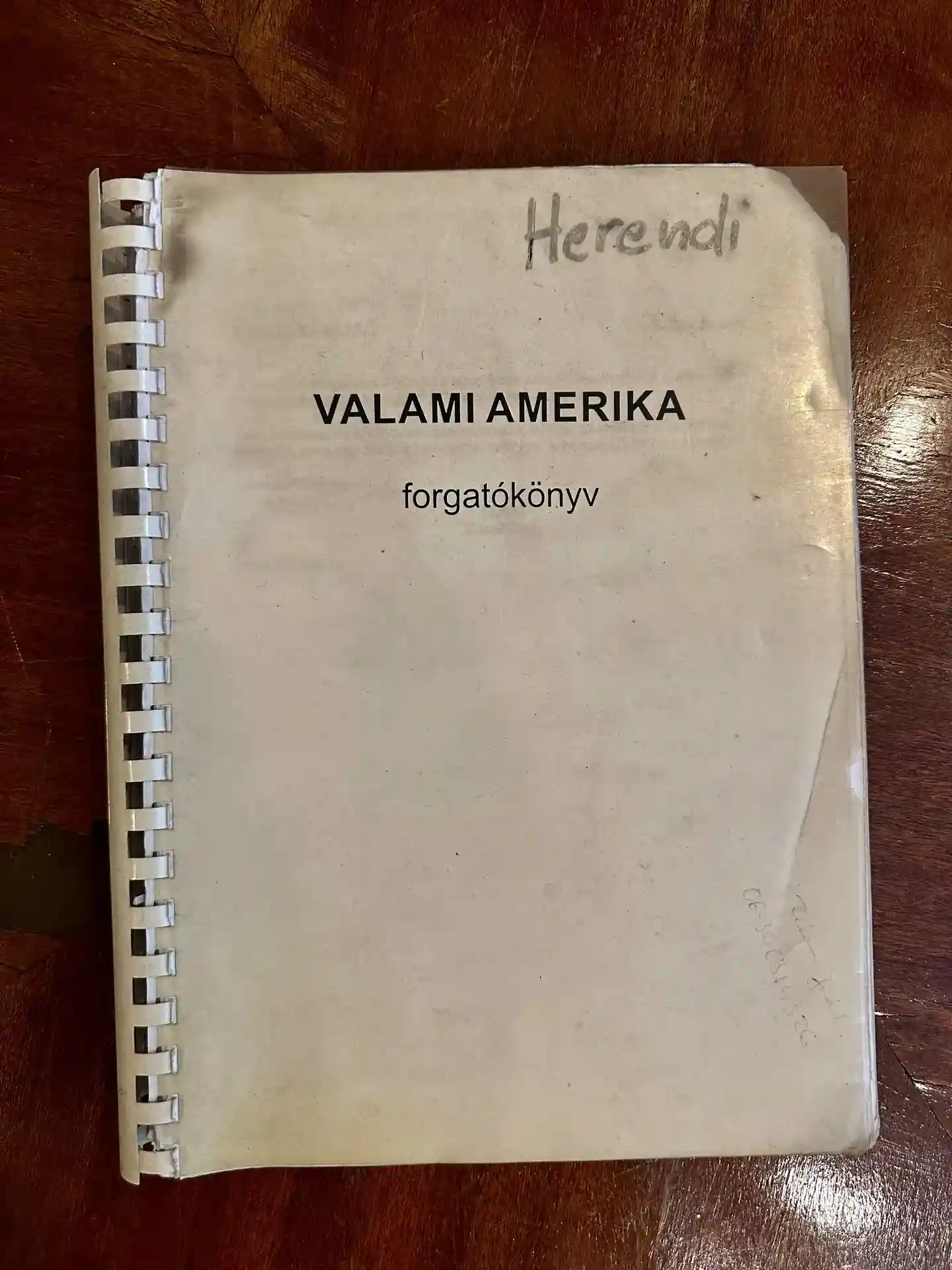 A spiral-bound script titled “Valami Amerika” lies on a wooden surface.