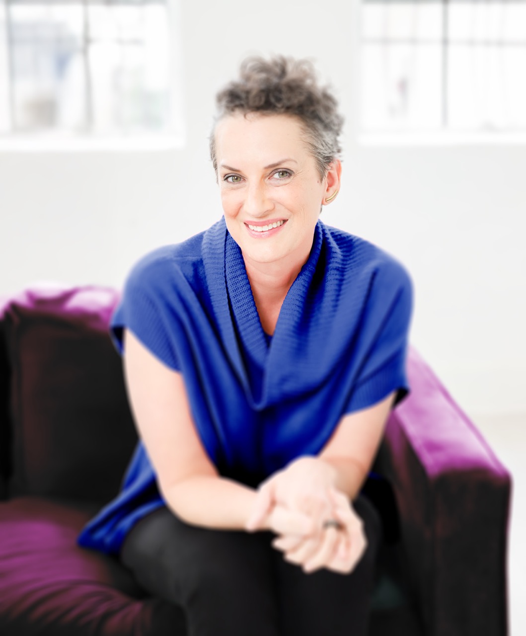 Color photo of Tessa siting on a purple couch with a blue shirt