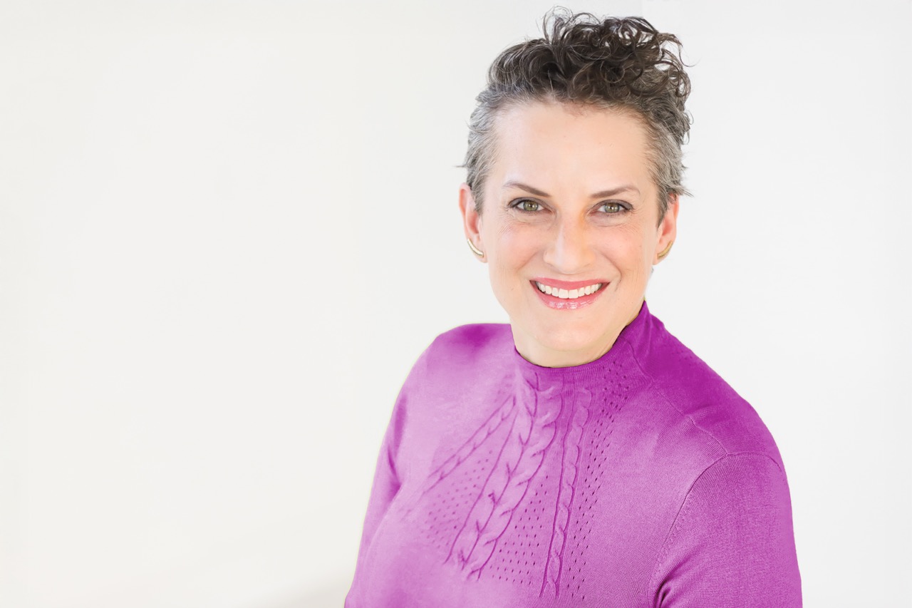 Close up color photo of Tessa in pink shirt smiling at camera