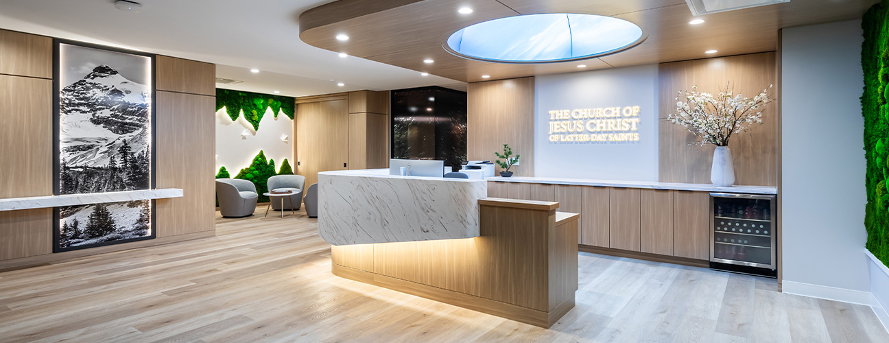 Modern spa reception with tan seating, round glass tables, marble accent wall, brass chandelier, and sleek front desk.