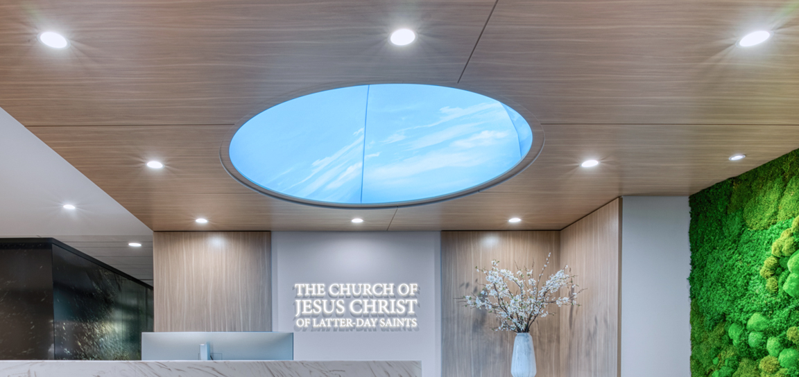 Modern spa reception with tan seating, round glass tables, marble accent wall, brass chandelier, and sleek front desk.