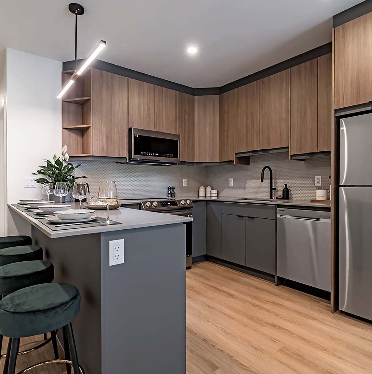 Modern condo kitchen with warm wood cabinets, matte grey island, stainless appliances, and sleek pendant lighting.