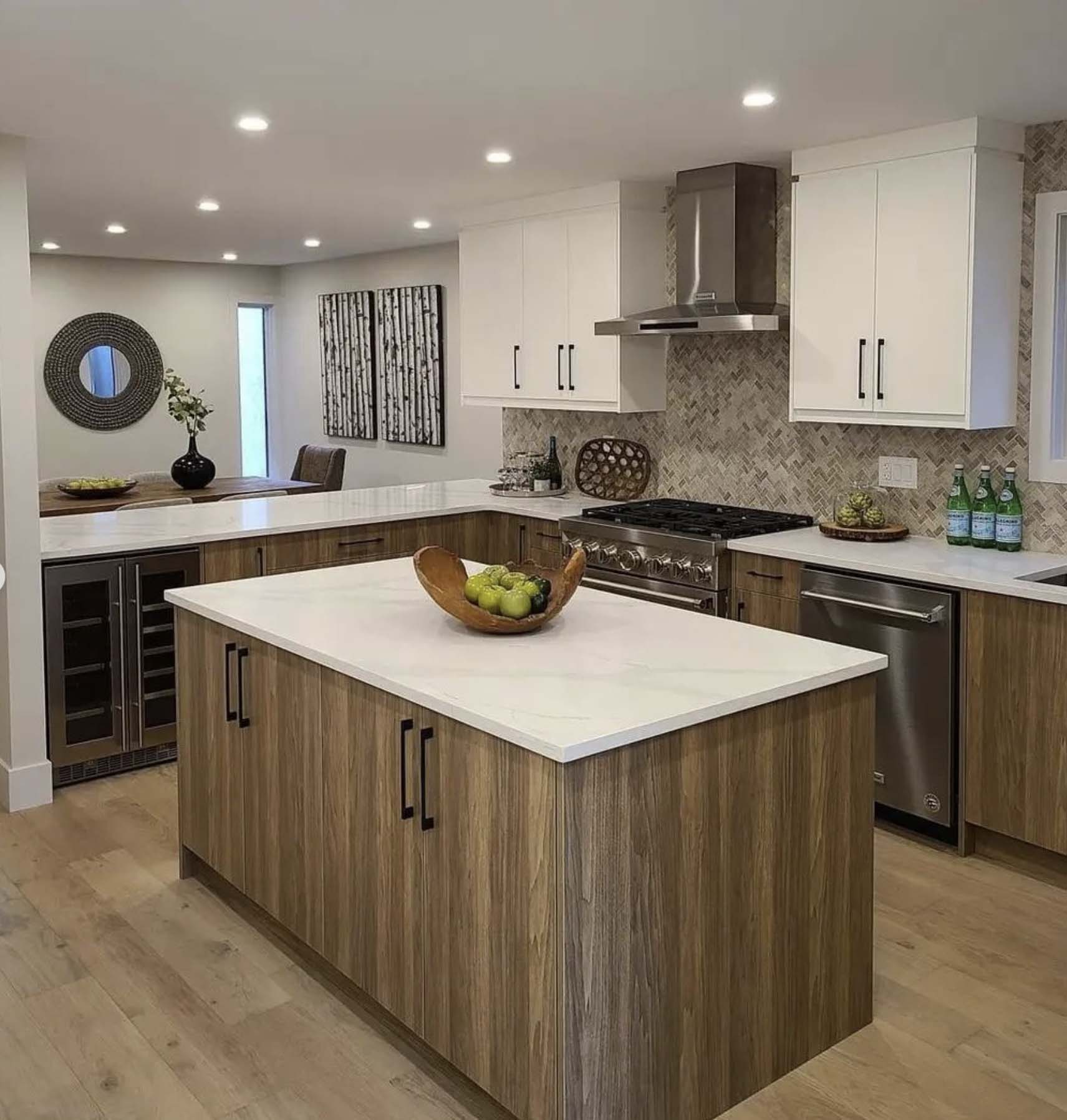 Modern kitchen with wood island, white quartz countertops, stainless appliances, patterned backsplash, and recessed lighting.