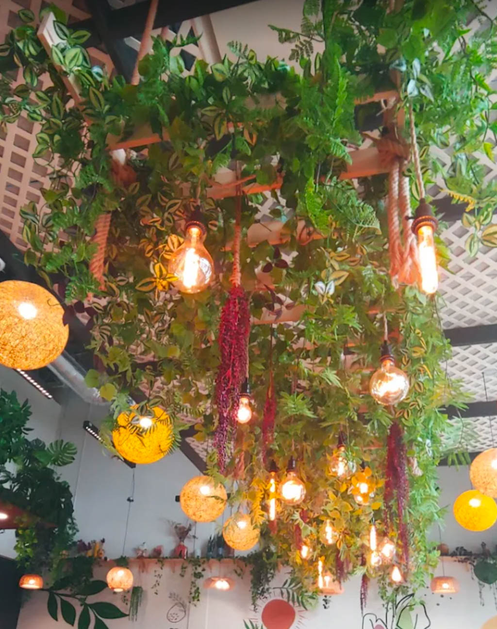 Lush ceiling greenery and glowing pendant lights create a warm, whimsical canopy overhead.