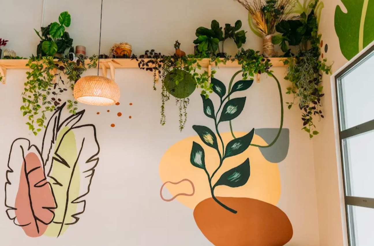 Playful botanical mural with trailing greenery and a woven pendant creates a warm, organic feature wall.