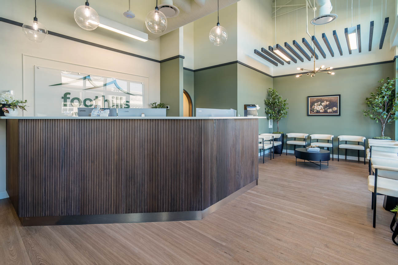 Bright, welcoming reception with soft greens, warm wood accents, and modern lighting for a calm first impression.