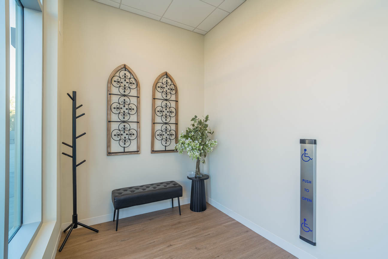 Bright entry nook with warm wood floors, decorative wall accents, bench seating, and accessible door control for ease and welcome.
