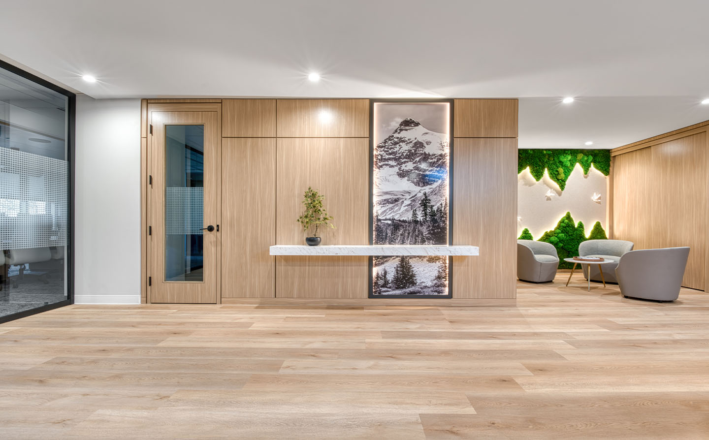 Reception wall with wood paneling, backlit mountain photography, floating marble shelf, and moss accent wall.