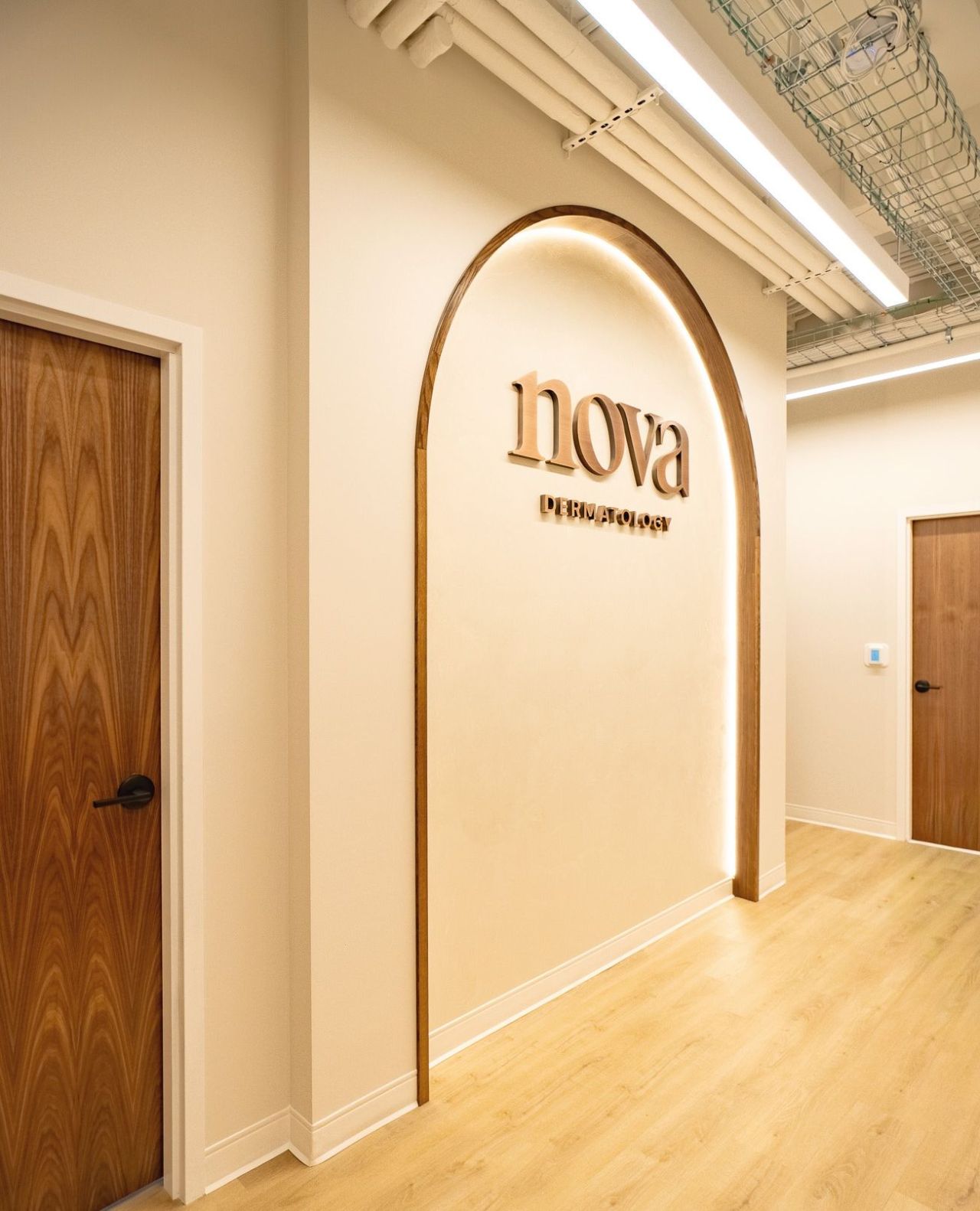 Wood-framed arch with backlight and Nova Dermatology signage on cream wall