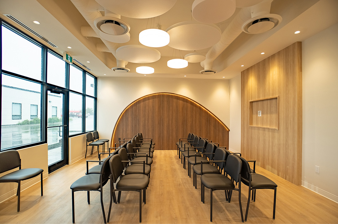 Waiting area with rows of black chairs, cloud-shaped ceiling panels, and wood arch focal wall