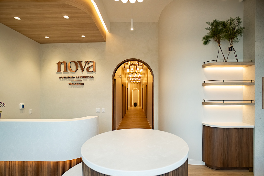 Nova Advanced Aesthetics reception with wood canopy ceiling, arched corridor view, and backlit shelving