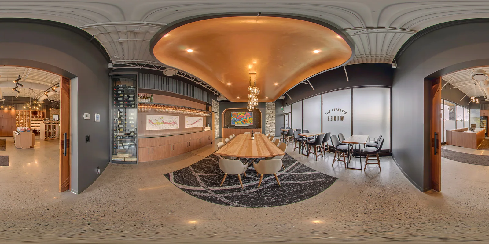 360° panorama of the tasting room with its curved copper ceiling, long oak table, wine cabinet, and glass-fronted wine storage, with the retail floor visible through the doorways.