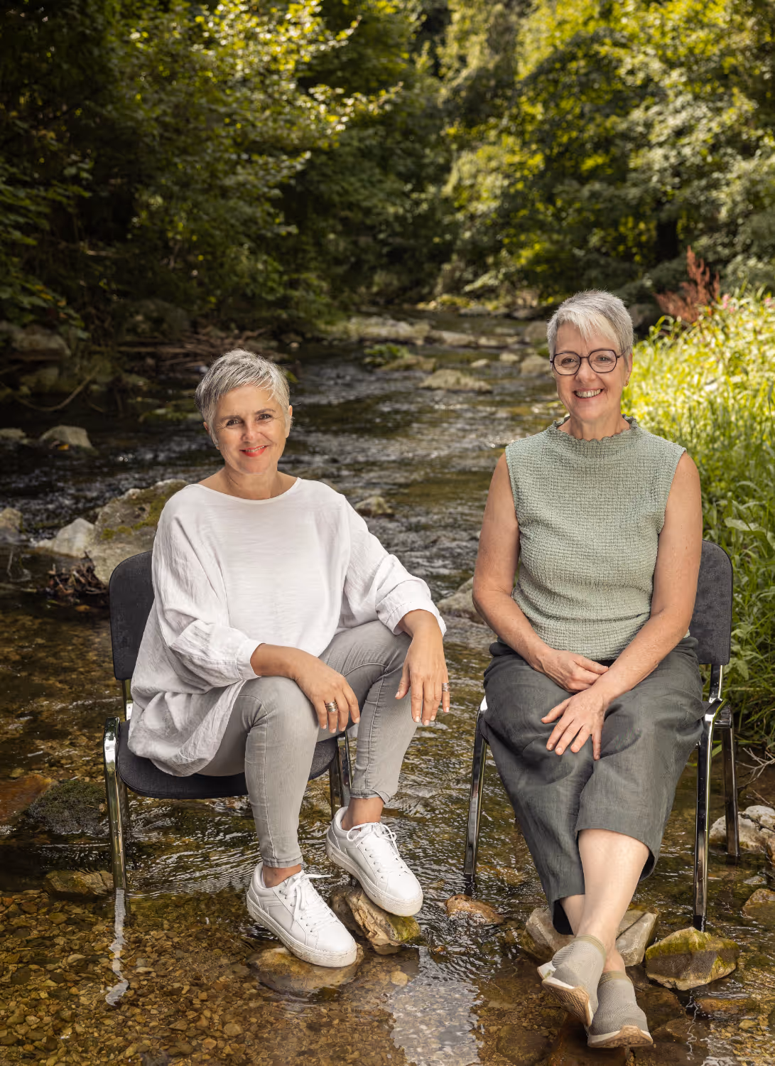 Sylvia und Angelika sitzen auf zwei Stühlen in einem Fluss
