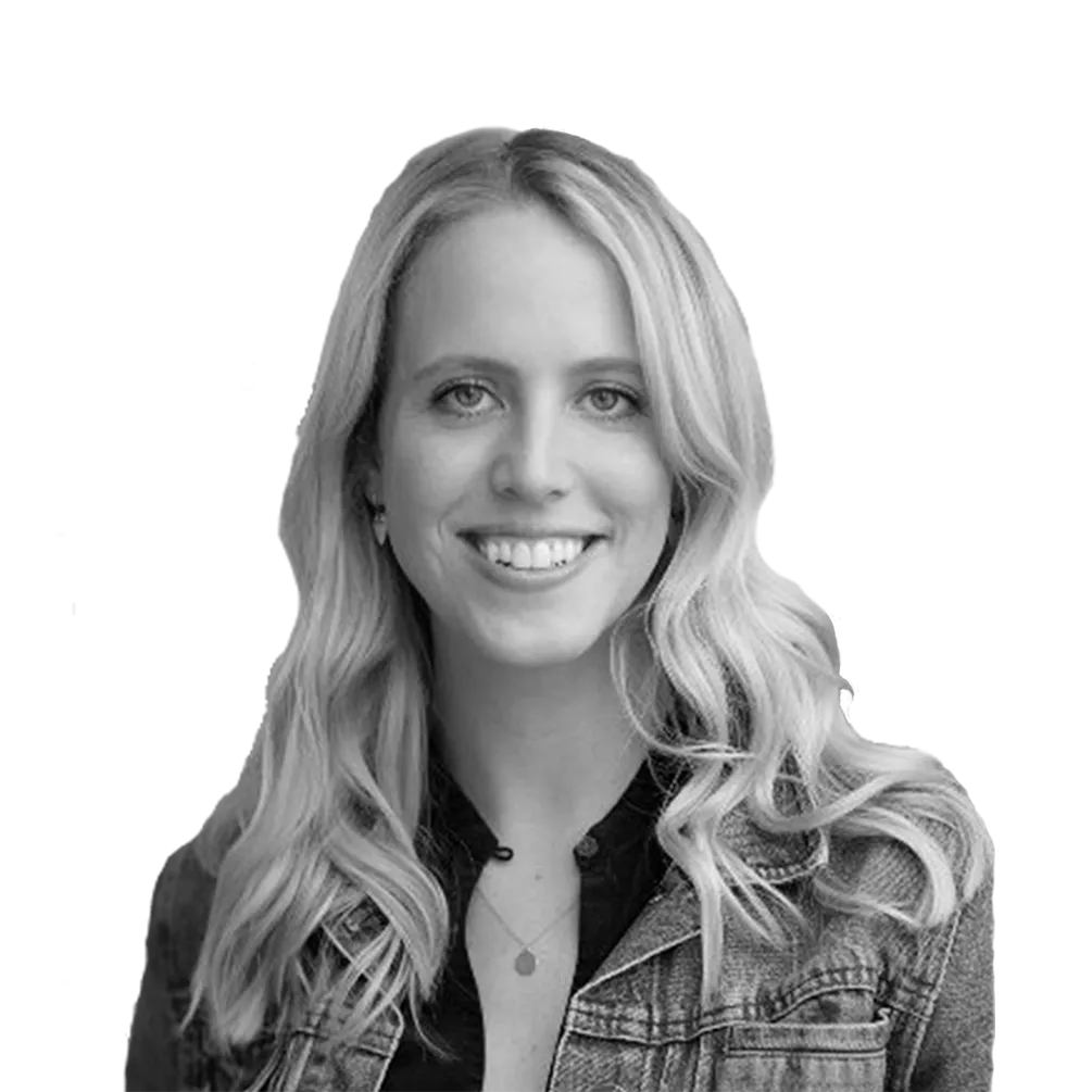 Smiling young woman with long wavy blonde hair wearing a denim jacket and a necklace.