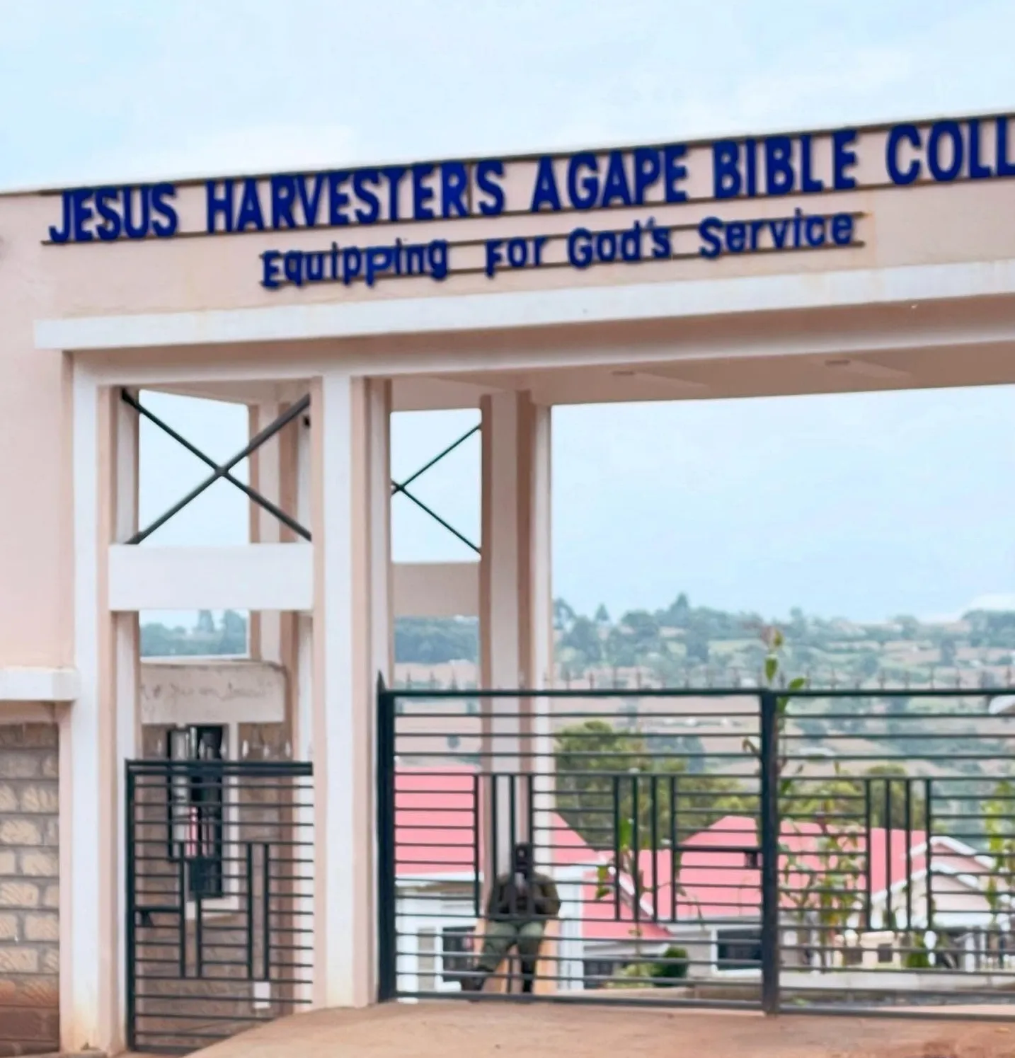 Entrance gate to Jesus Harvesters Agape Bible College with slogan 'Equipping for God's Service' above the gate.