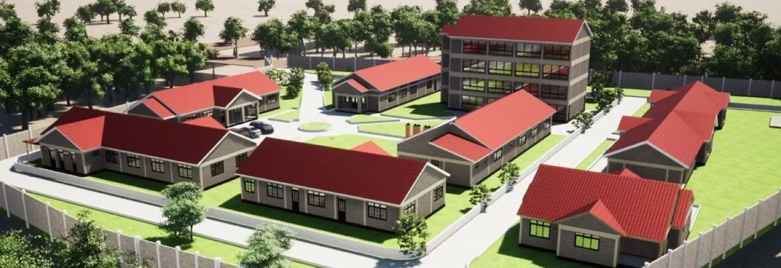 Aerial view of a fenced compound with multiple single-story buildings and one multi-story building, all with red roofs, surrounded by trees and pathways.