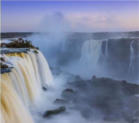 Vista panorámica de cataratas con agua cayendo y niebla en un paisaje natural.