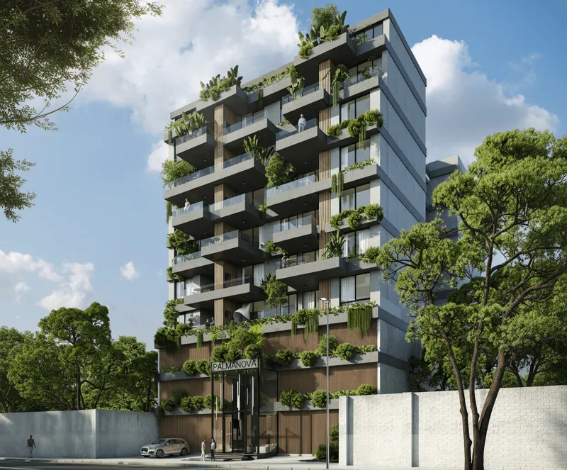 Edificio moderno de varios pisos con balcones amplios y plantas verdes en cada nivel, rodeado de árboles y cielo azul con nubes.