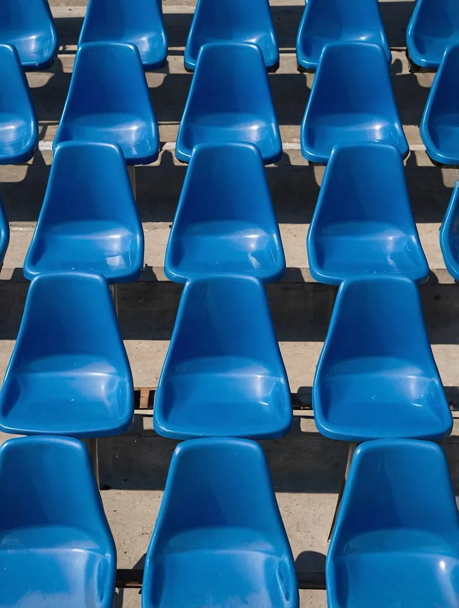 A row of blue plastic seats sitting on top of a cement floor.