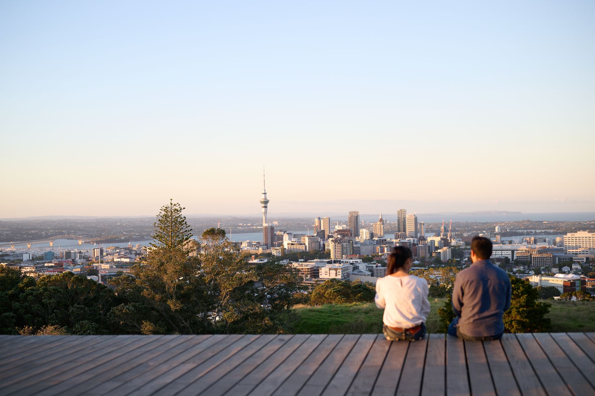 Couple on a visitor visa, smiling while resting on the top of a mountain