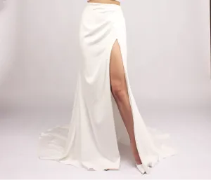 White floor-length skirt with a high slit revealing the leg.
