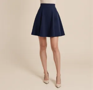 Woman wearing a navy blue high-waisted A-line skirt with beige pointed-toe heels.