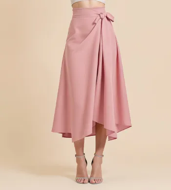 Woman wearing a strapless white top and a high-low pink skirt with a tied detail on one side, standing against a beige background.