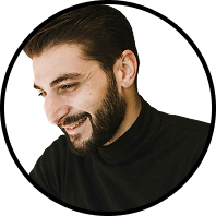 Smiling man with dark hair and beard wearing a black turtleneck, looking down and to the left.