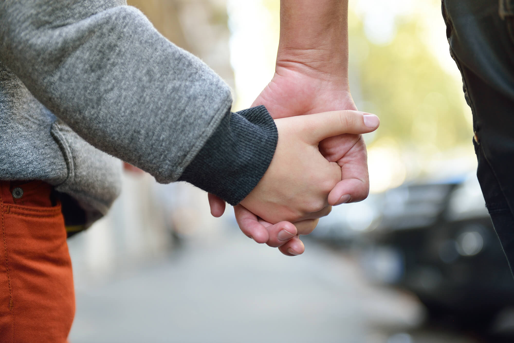Close-up of a child holding hands with their mother.