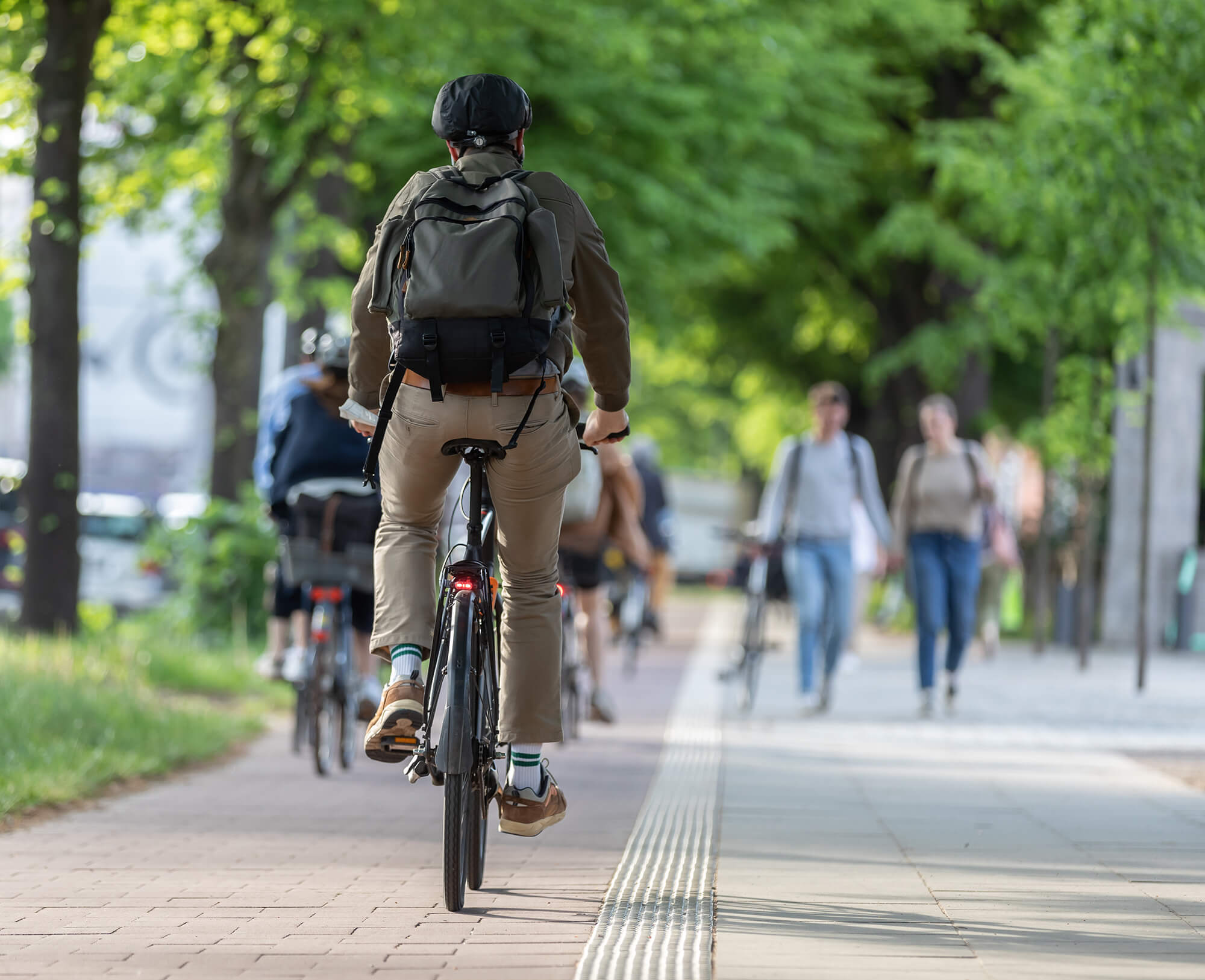 Cyclist on a shared pedestrian and bike path surrounded by trees.