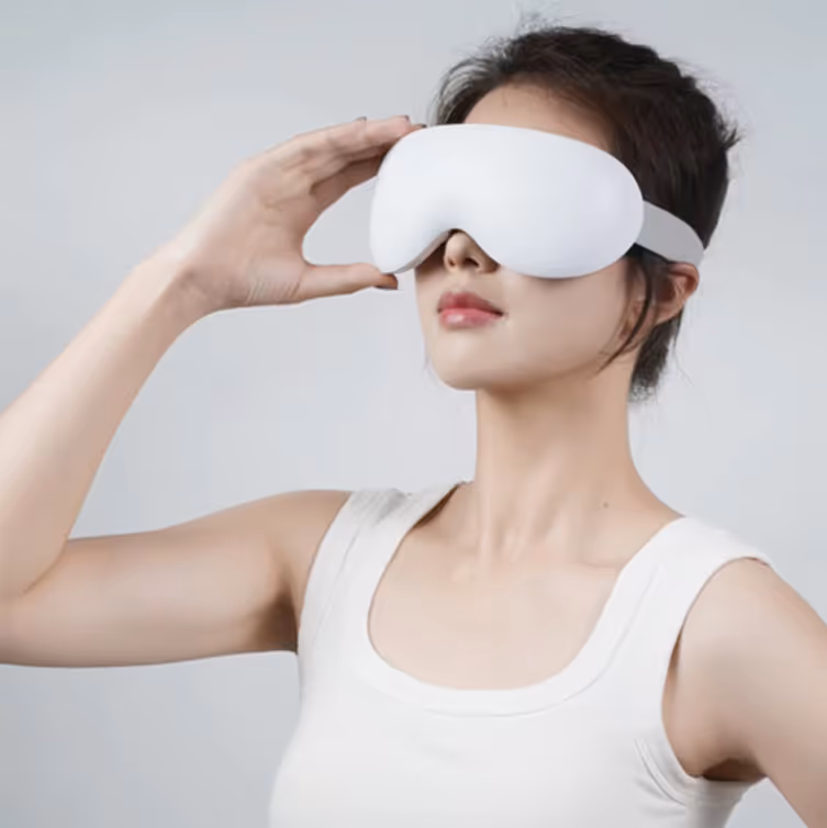 Mujer usando una máscara para ojos blanca ajustándola en un fondo neutro.