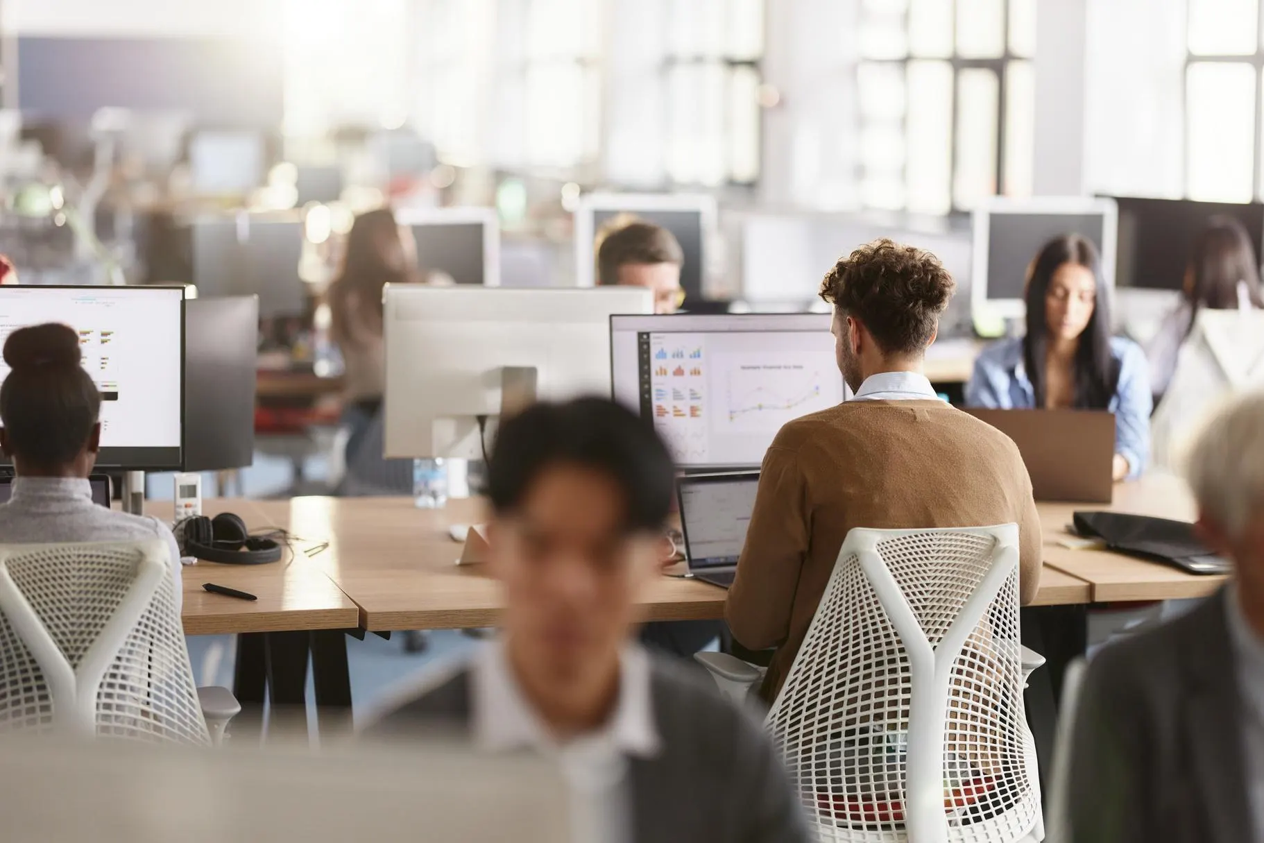 Out of focus photo of an open-concept office with people working at computers