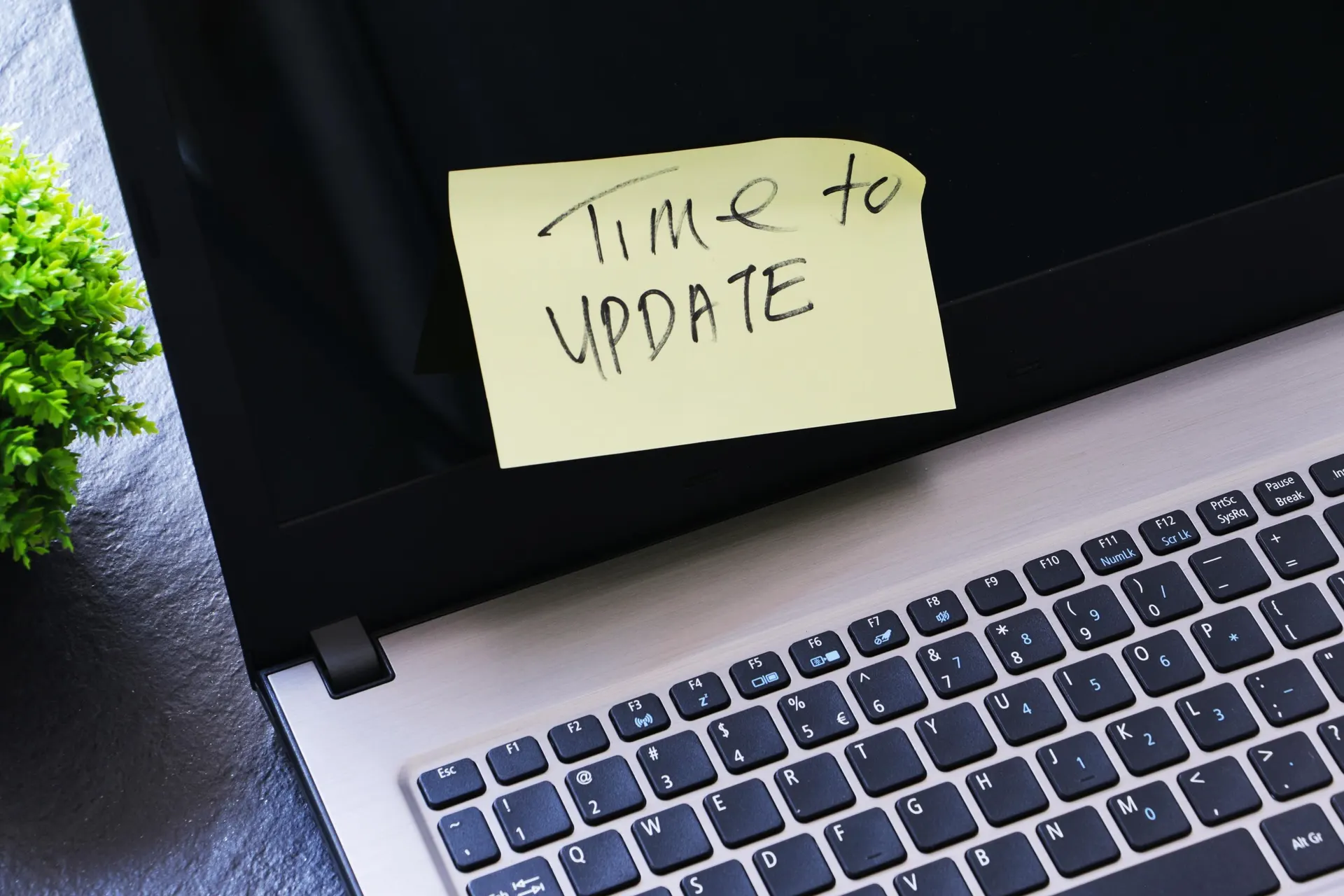 Close-up of a laptop with a sticky-note on it. The note reads "Time to update."