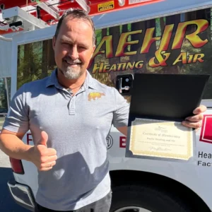 Man in gray polo shirt giving thumbs up and holding a certificate standing in front of a heating and air service van.