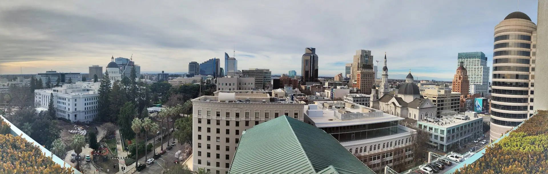 Panoramic view of Sacramento city skyline with a mix of historic and modern buildings under a cloudy sky.