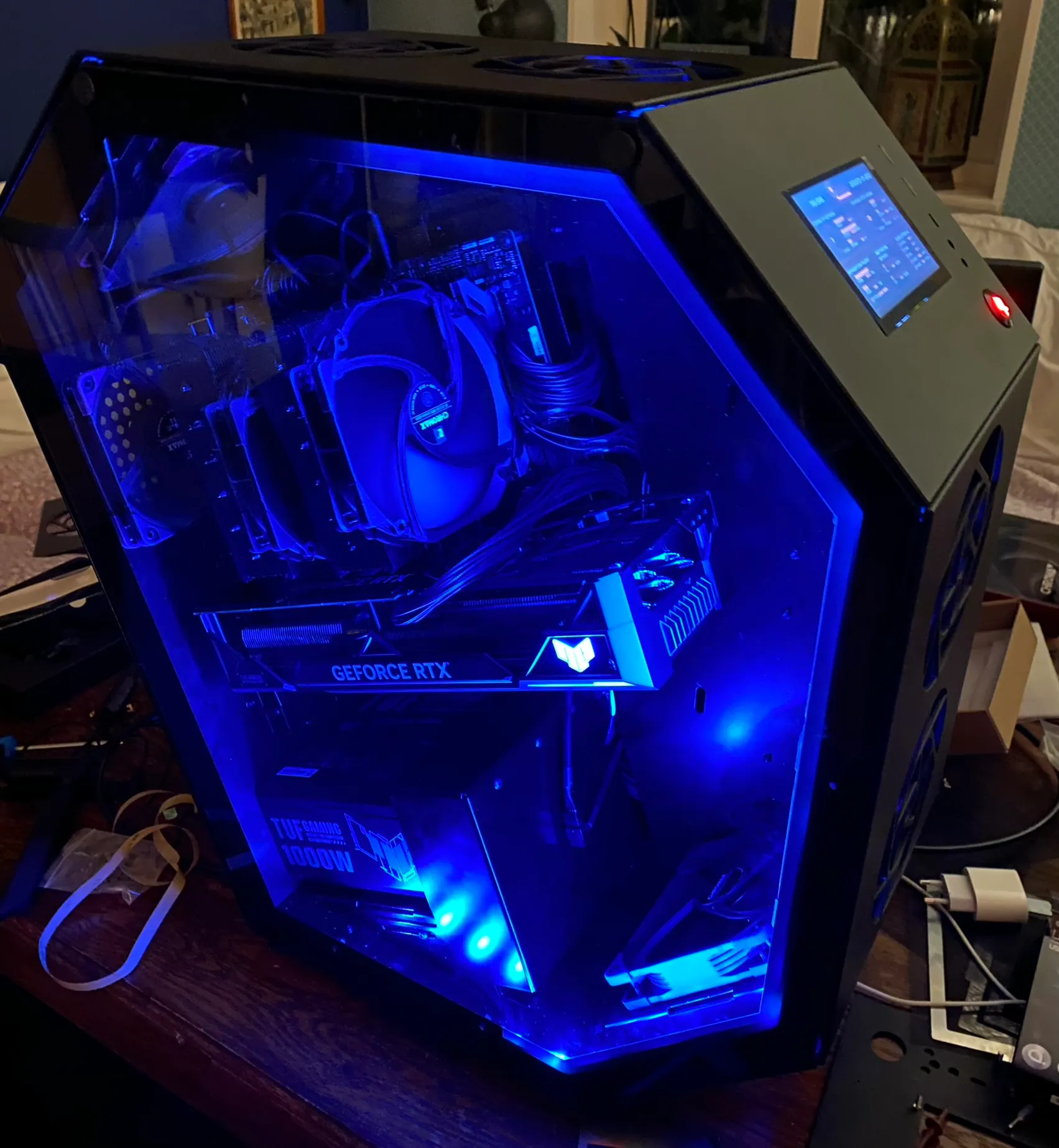 Gaming PC with blue internal LED lighting showing GeForce RTX graphics card and TUF Gaming 1000W power supply.