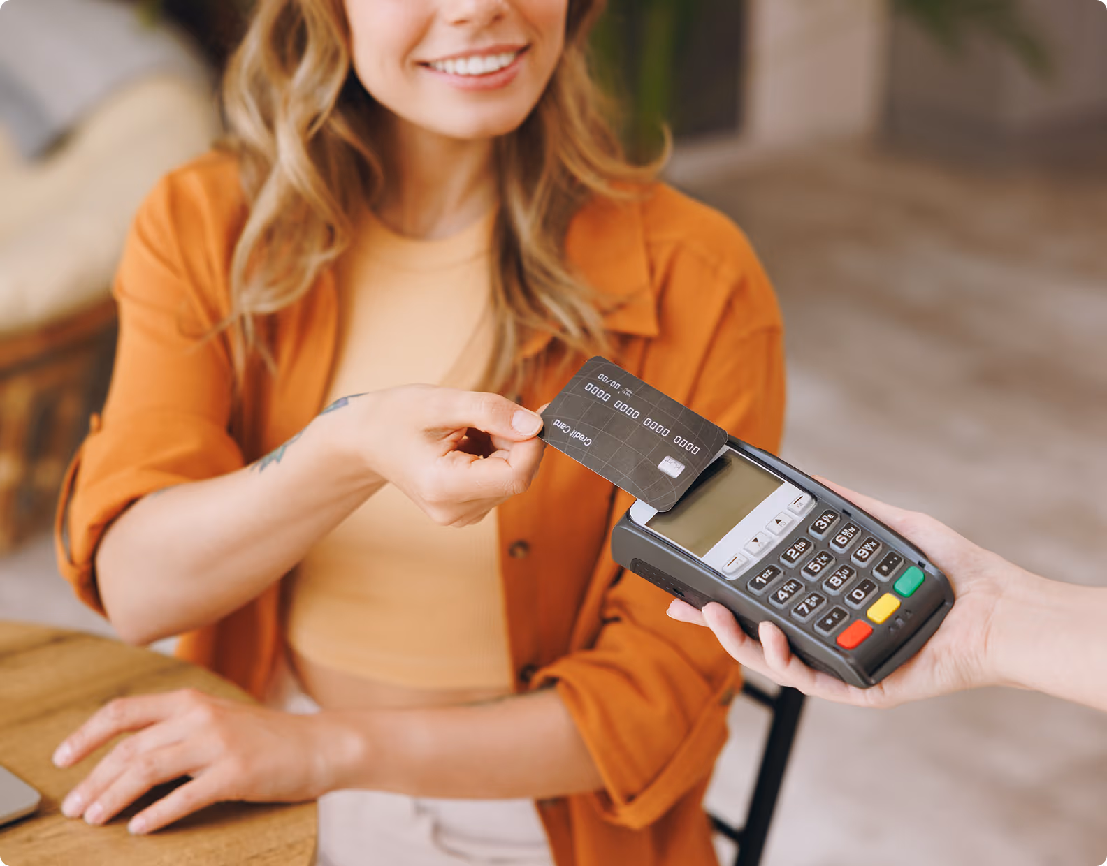 Woman holding a credit card near a payment terminal for contactless payment.