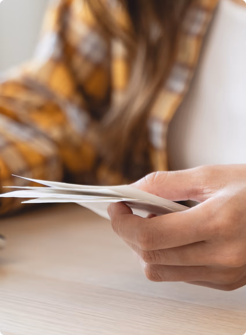 Person holding and flipping through several white cards or papers.