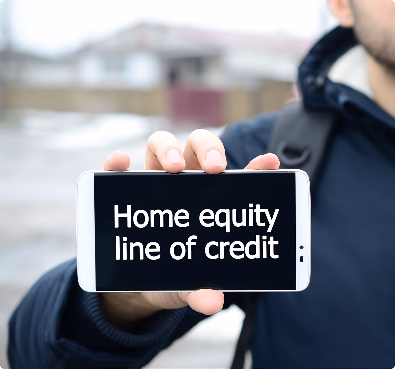 Person holding a smartphone displaying the text 'Home equity line of credit'.