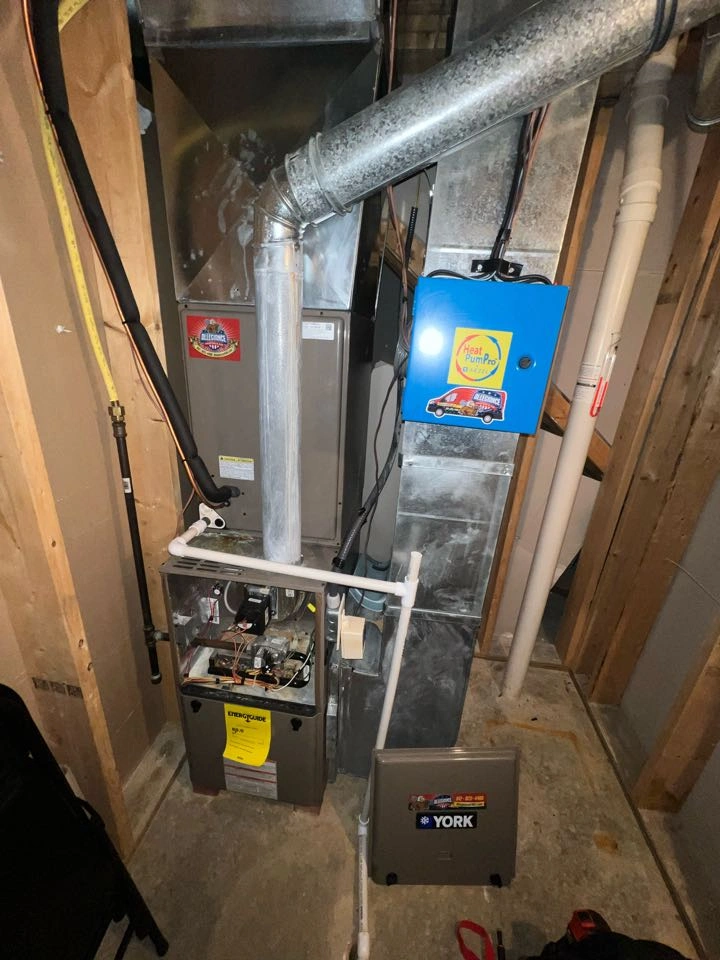 Basement furnace setup with exposed ducts and pipes. A blue box labeled "Heat Pump Pro" is attached.