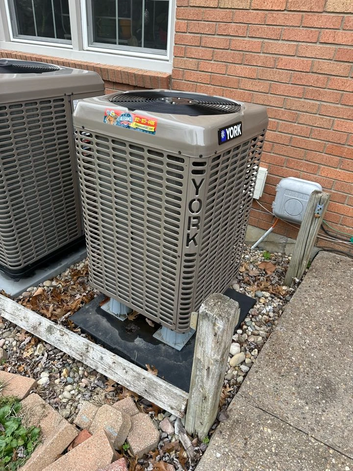 Two beige York air conditioning units are placed outside a red brick building.