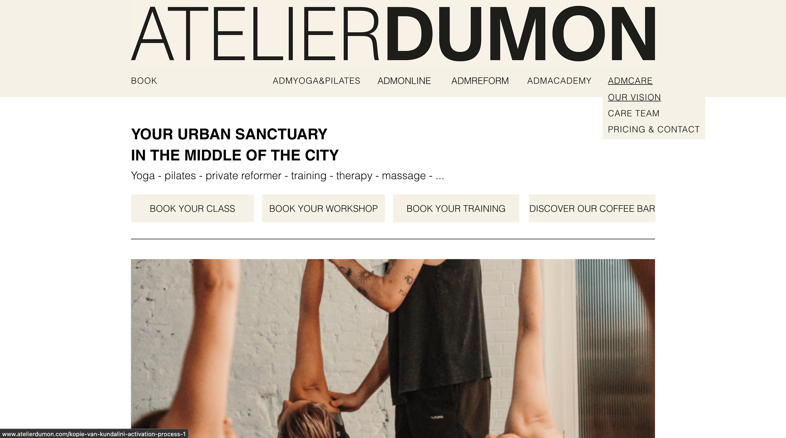 Website header for Atelier Dumon with navigation menu and a photo of a person assisting another in a stretch or yoga pose indoors.