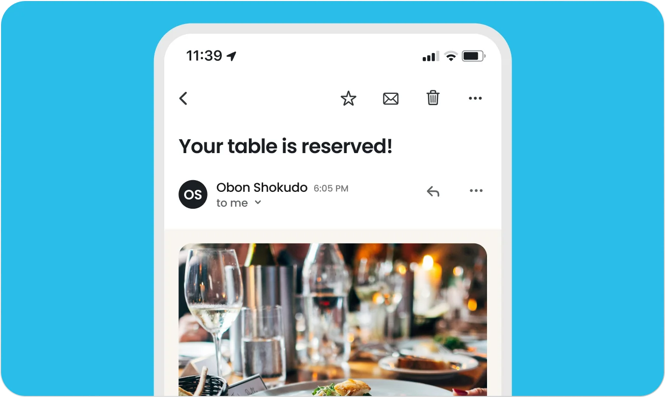 Email on smartphone screen showing a restaurant reservation confirmation from Obon Shokudo with a photo of a table setting including wine glasses and a plated dish.
